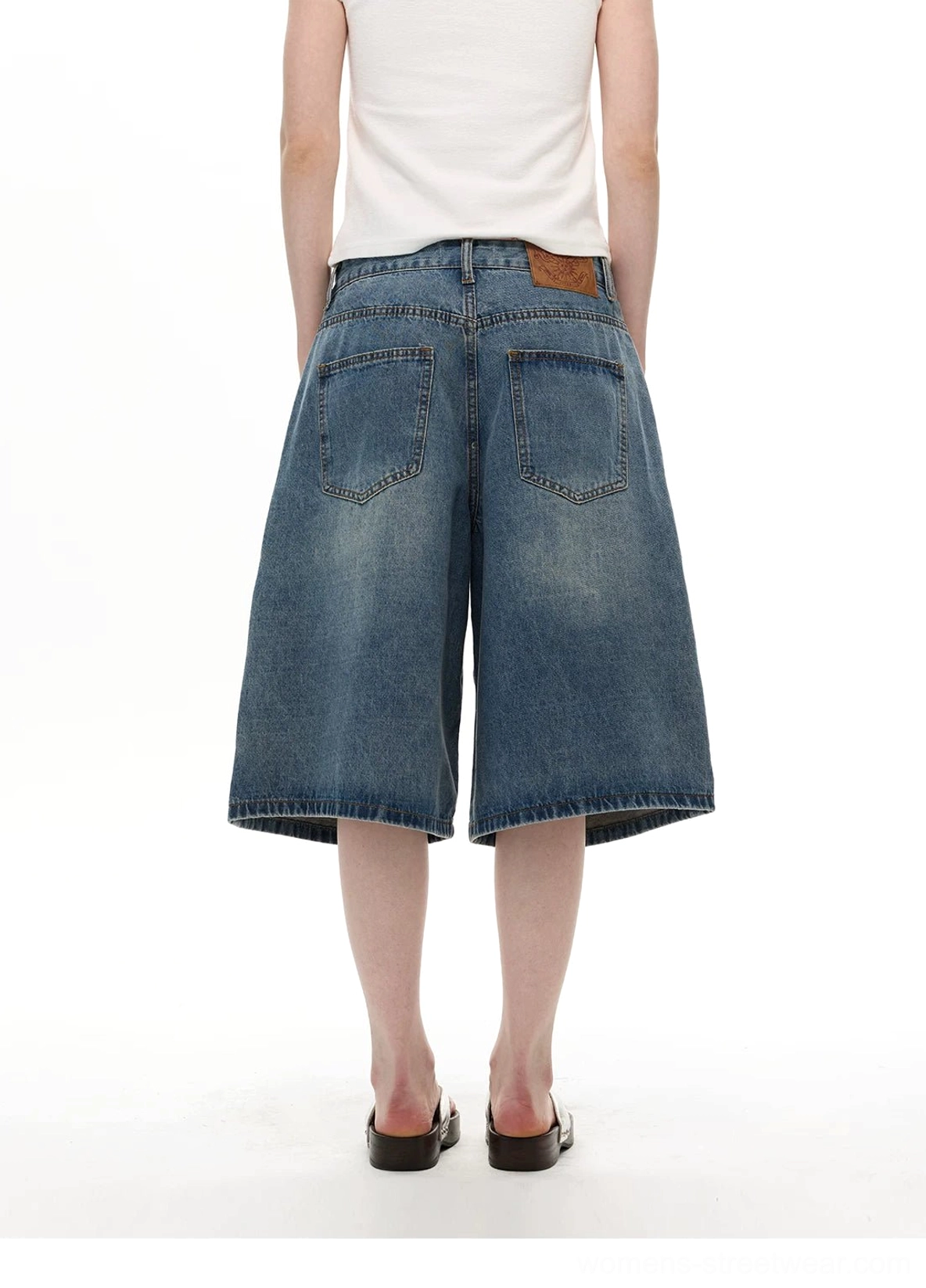 Light wash wide-leg denim knee shorts back view with dual pockets and leather waistband patch