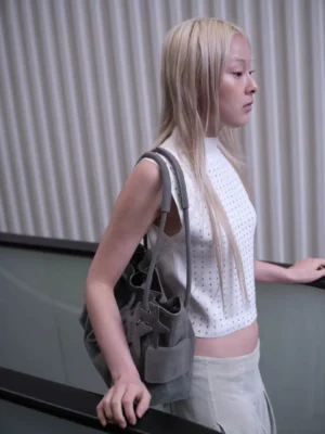 Ash gray textured PU leather drawstring cloud shoulder bag side profile in an urban shopping mall