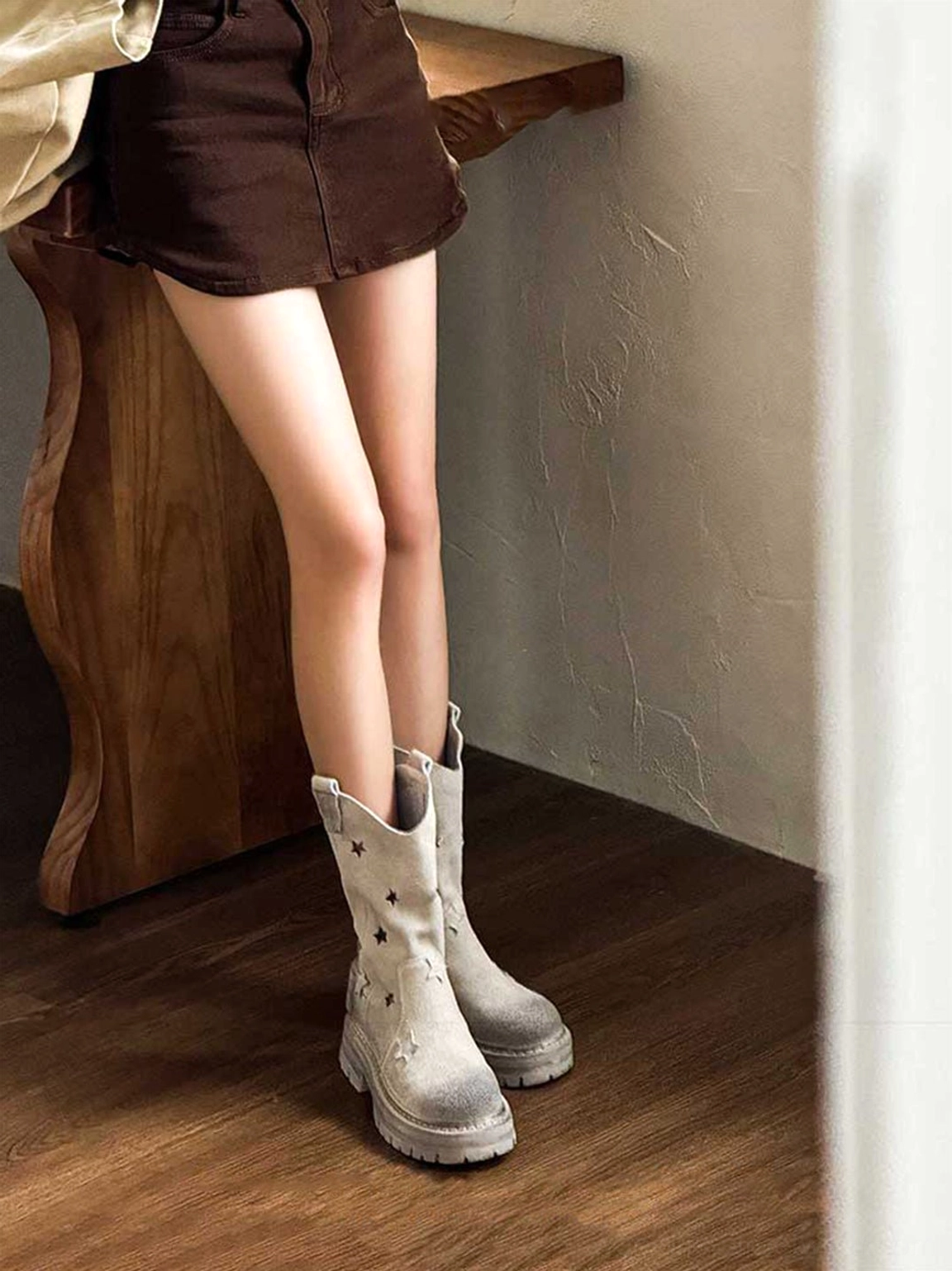Star platform mid-calf boots front side standing view with model in mini skirt outfit on wooden floor showing elevation effect