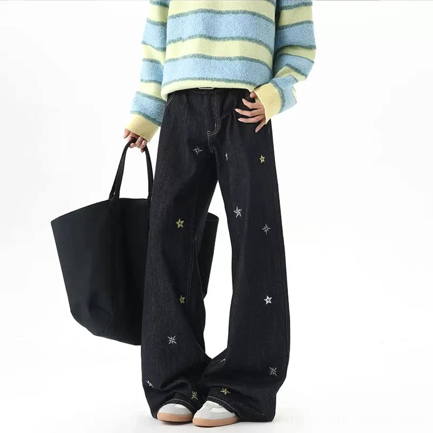 Front three-quarter view of star embroidery wide-leg jeans styled with a striped sweater, sneakers, and black tote bag
