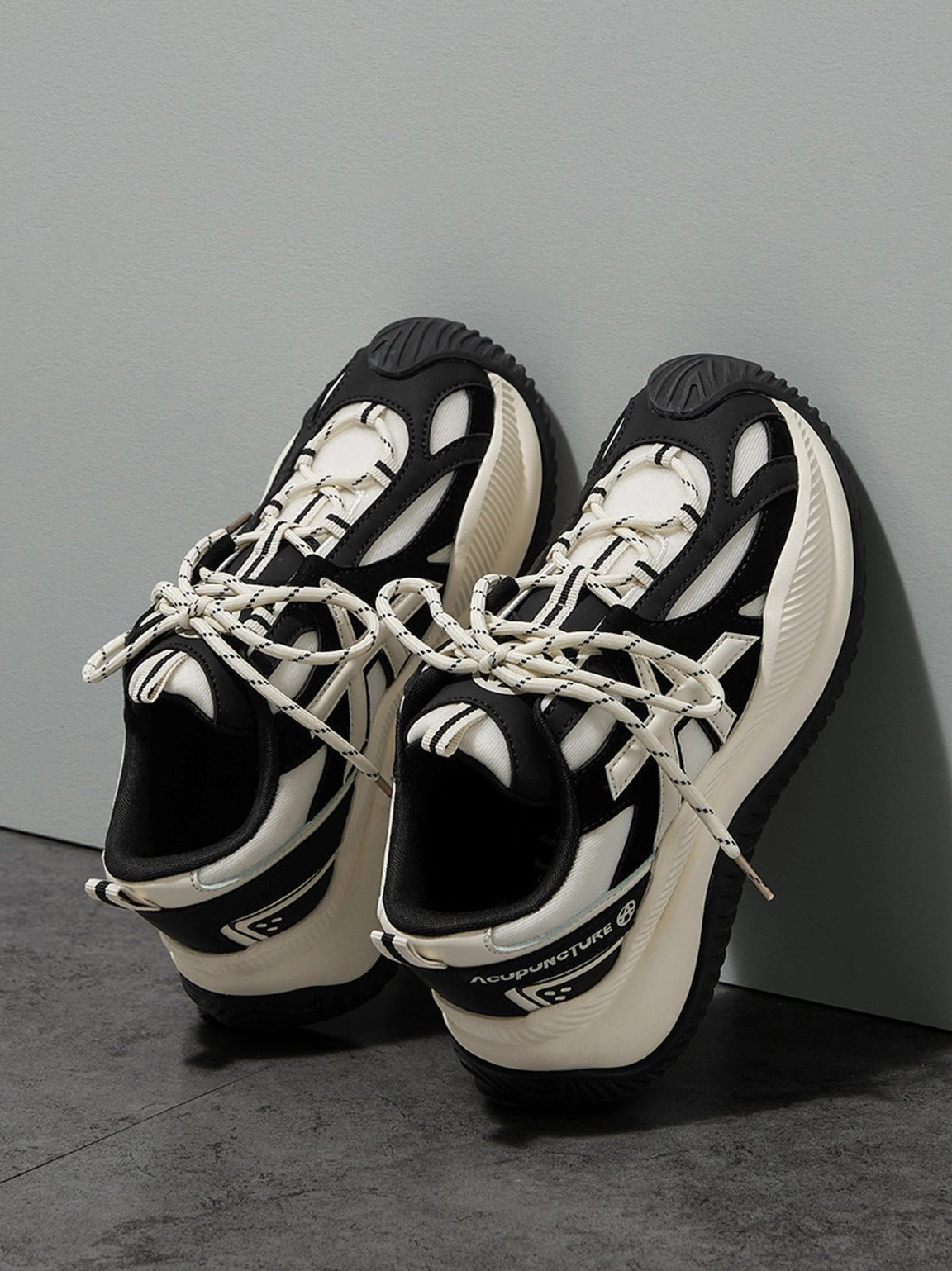 Side oblique leaning display of wave-sole sneakers profile view showing brand text on heel and wave-patterned thick outsole texture