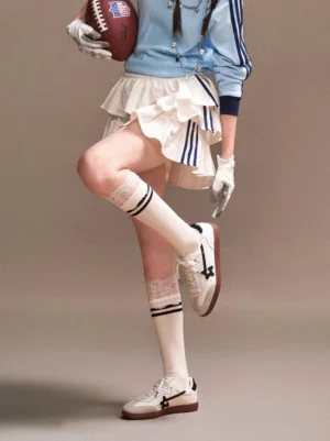 Female athlete wearing white star-panel low-profile streetwear trainers with striped socks in a sporty retro outfit