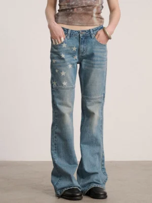 Front view of blue low-rise star panel flare jeans with faded denim wash, fitted upper leg, white star graphics, and flared hems