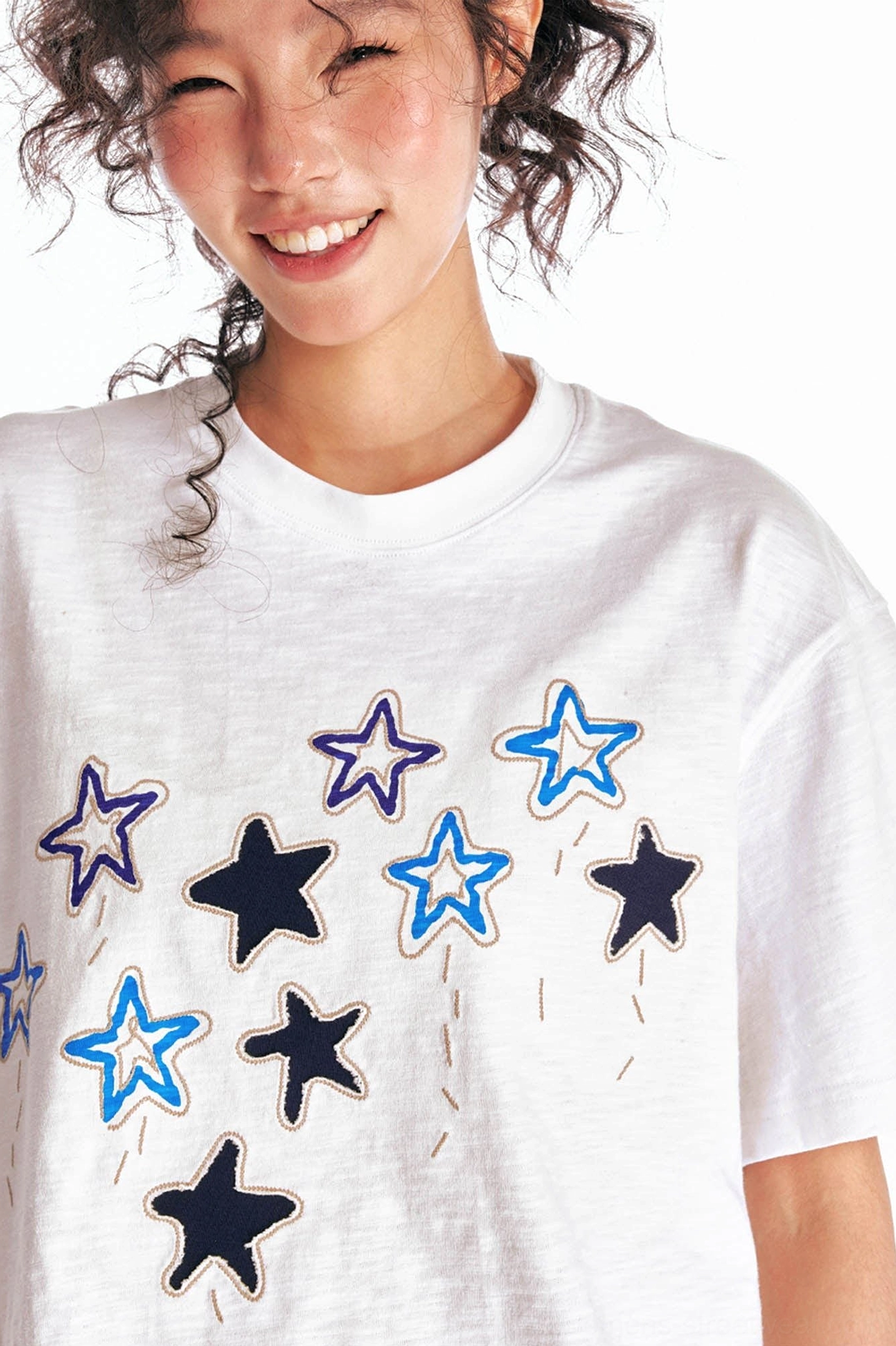 Close up of mixed blue outline and dark solid star embroidery on white oversized crewneck cotton streetwear tee