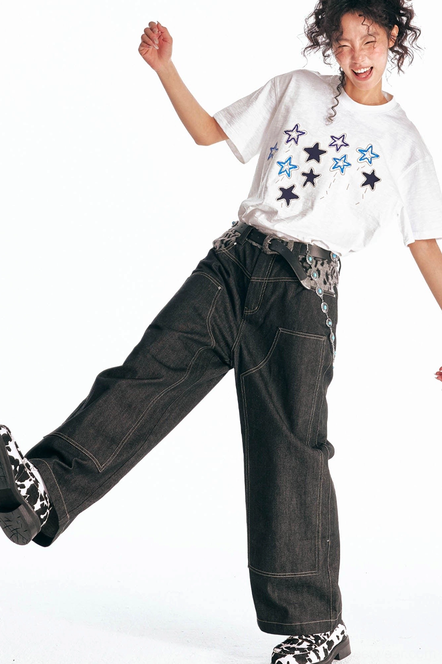 Star parade white cotton streetwear tee styled with black wide leg denim and checkerboard sneakers action outfit view