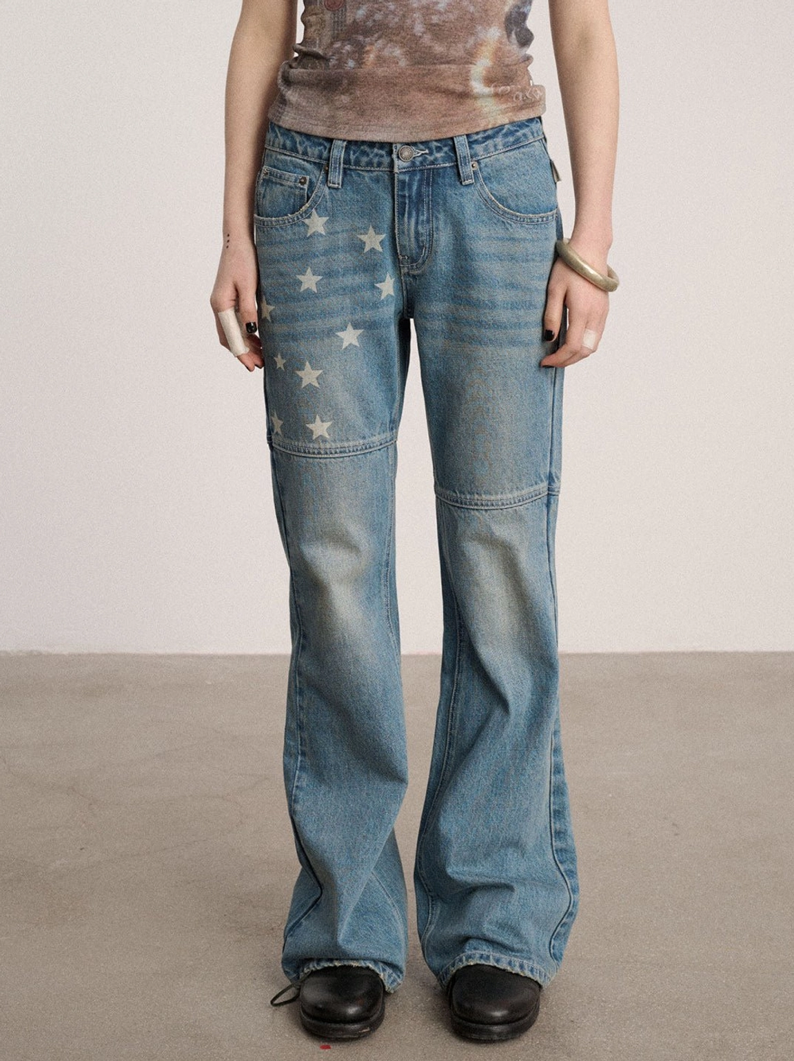 Close front view of star patterned low-rise flare jeans with five-pocket construction, worn blue wash, and bootcut silhouette