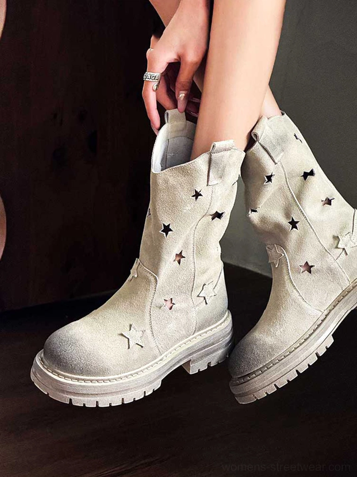 Pair of perforated-star nubuck platform boots side three-quarter static view on dark brown wooden background showing star cutout texture
