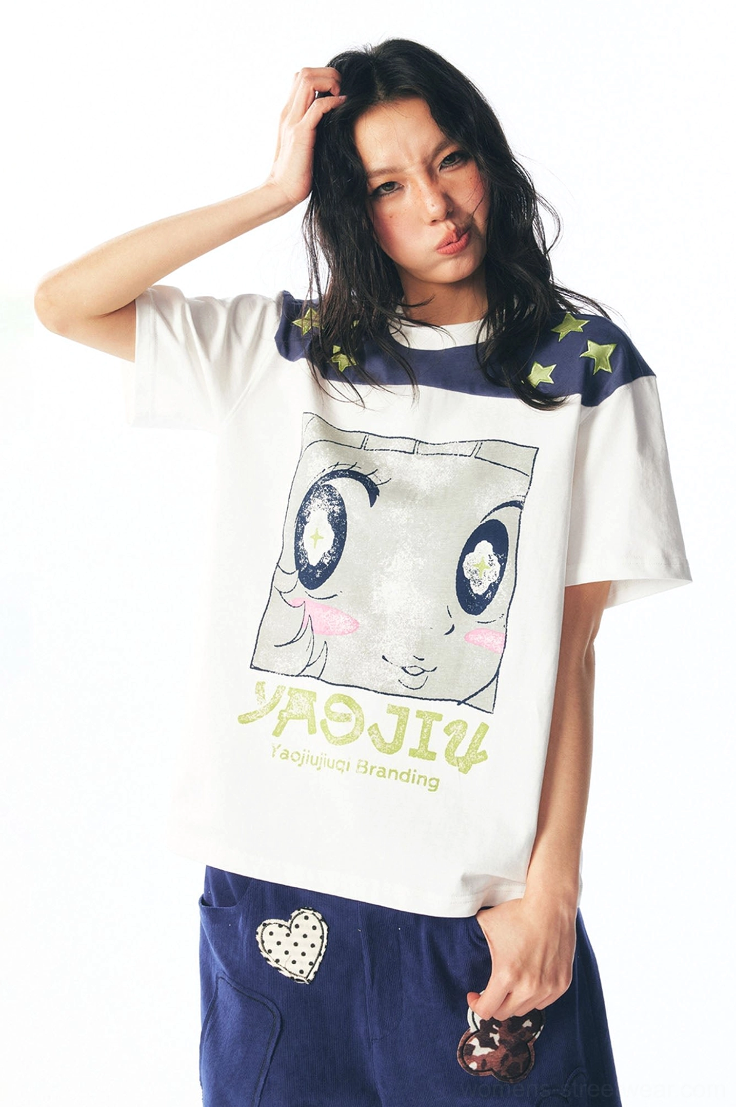 Close front view of cartoon face artwork and navy star shoulder panel on white streetwear tee