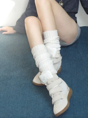 Model wearing off-white star Velcro hidden-wedge high-top sneakers with slouchy white crew socks on blue carpet