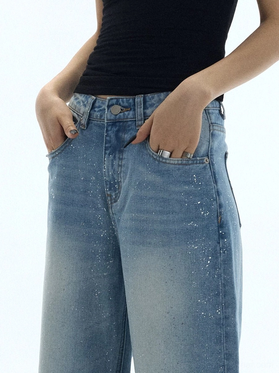 Close-up front waist view of washed blue glitter wide-leg jeans with subtle speckled sparkle and classic pockets