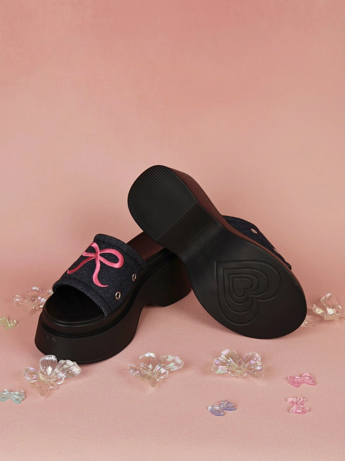 Statement platform slide sandals featuring bow embroidery, eyelet accents, and a playful hot pink colorway