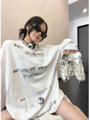 White oversized graphic long sleeve T-shirt with reversed black typography, shown with silver sneakers for a Y2K streetwear outfit