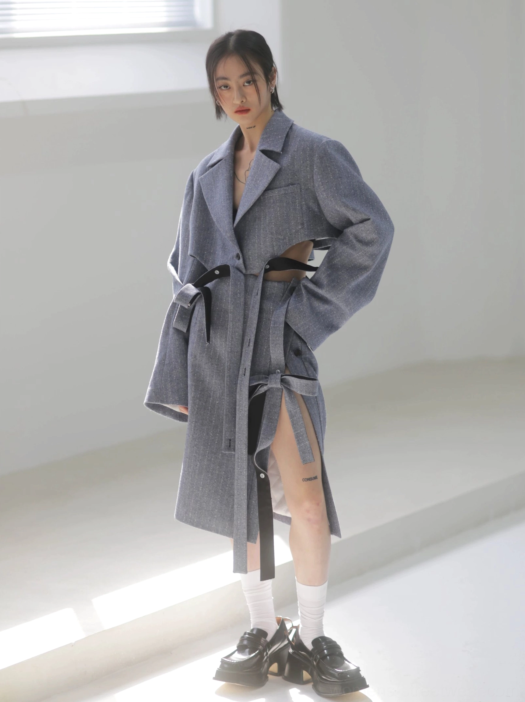 Steel blue herringbone pencil midi skirt styled with a tailored long coat, showing the side profile, elegant midi length, and adjustable ribbon slit detail