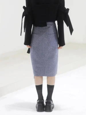 Back and lower-body view of a steel blue herringbone tailored midi skirt with a straight pencil shape, textured suiting fabric, and sleek structured finish