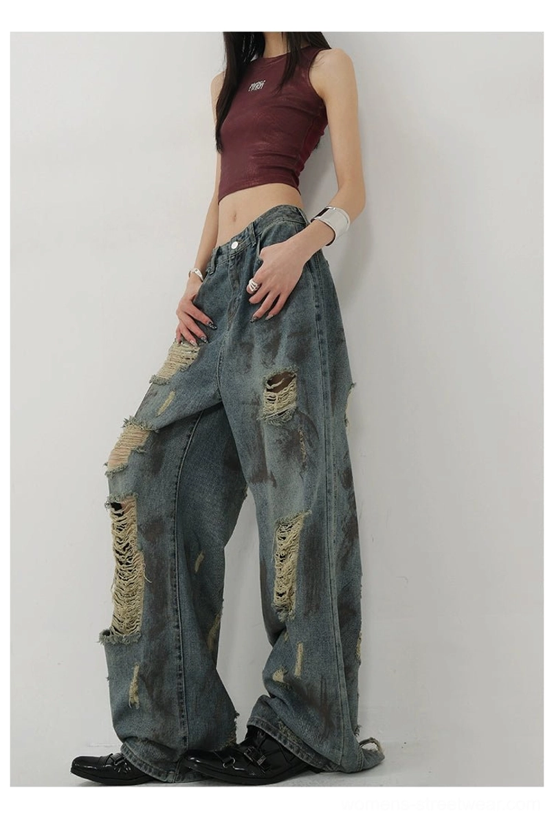 Streetwear blue distressed denim jeans with a roomy draped leg, vintage wash, and expressive frayed texture