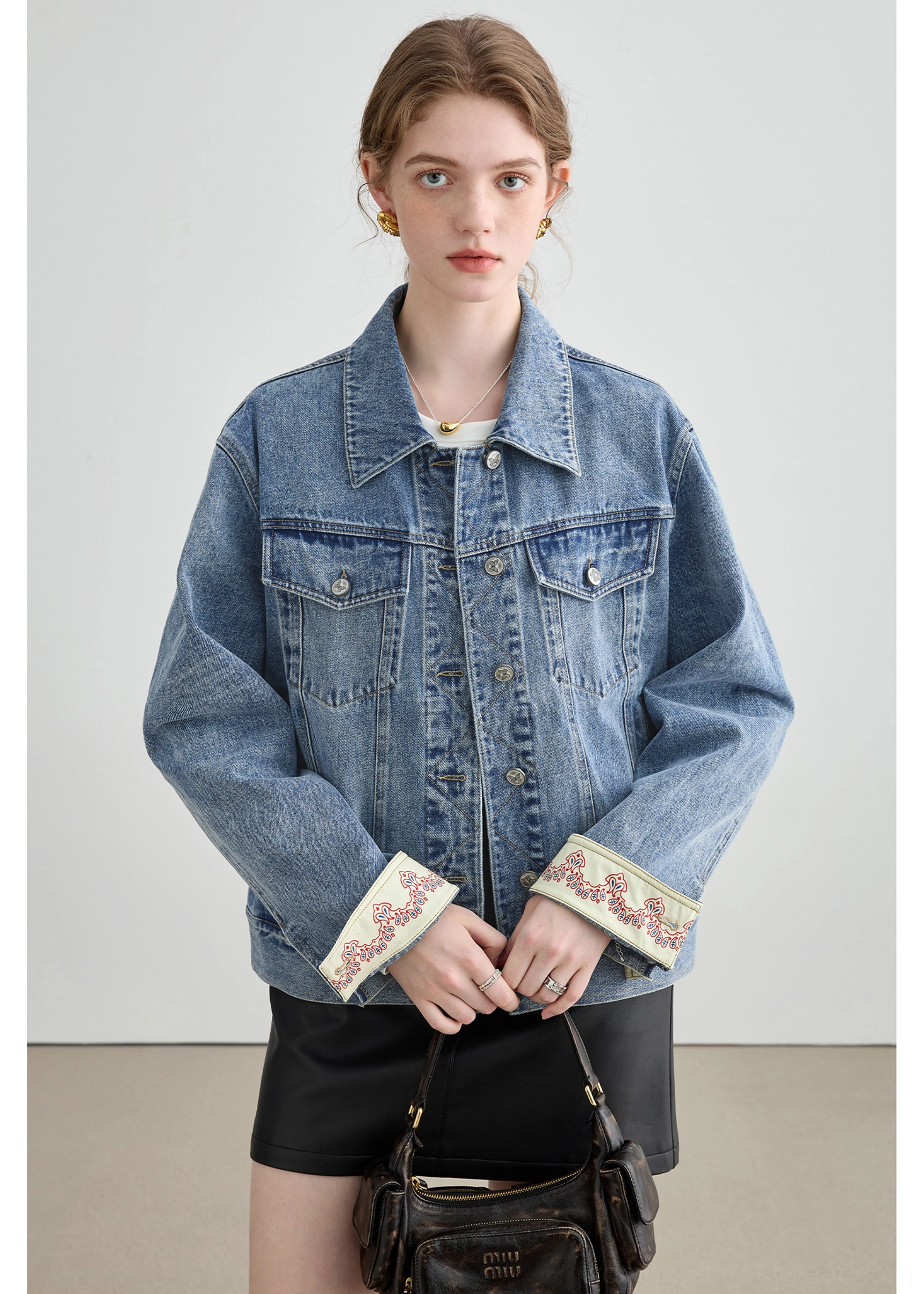 Streetwear denim jacket detail showing structured collar, full button placket, chest patch pockets, and textured cotton fabric