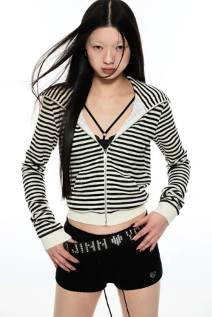 Half-body view of a woman wearing a cropped black and white striped cat ear streetwear hoodie layered over a lace bralette