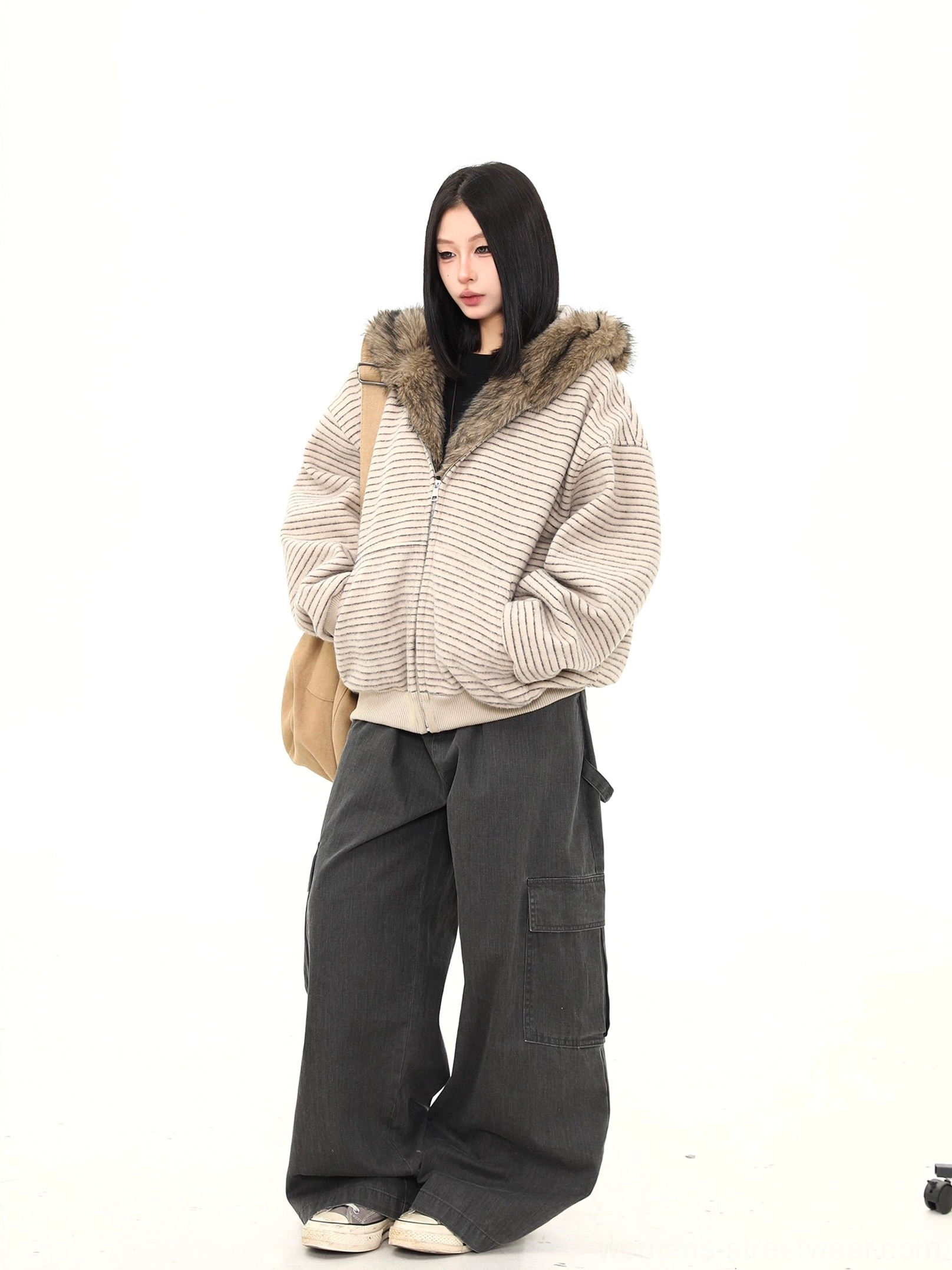 Side three quarter view of a striped faux fur hooded winter jacket with front pockets cargo pants and canvas shoes