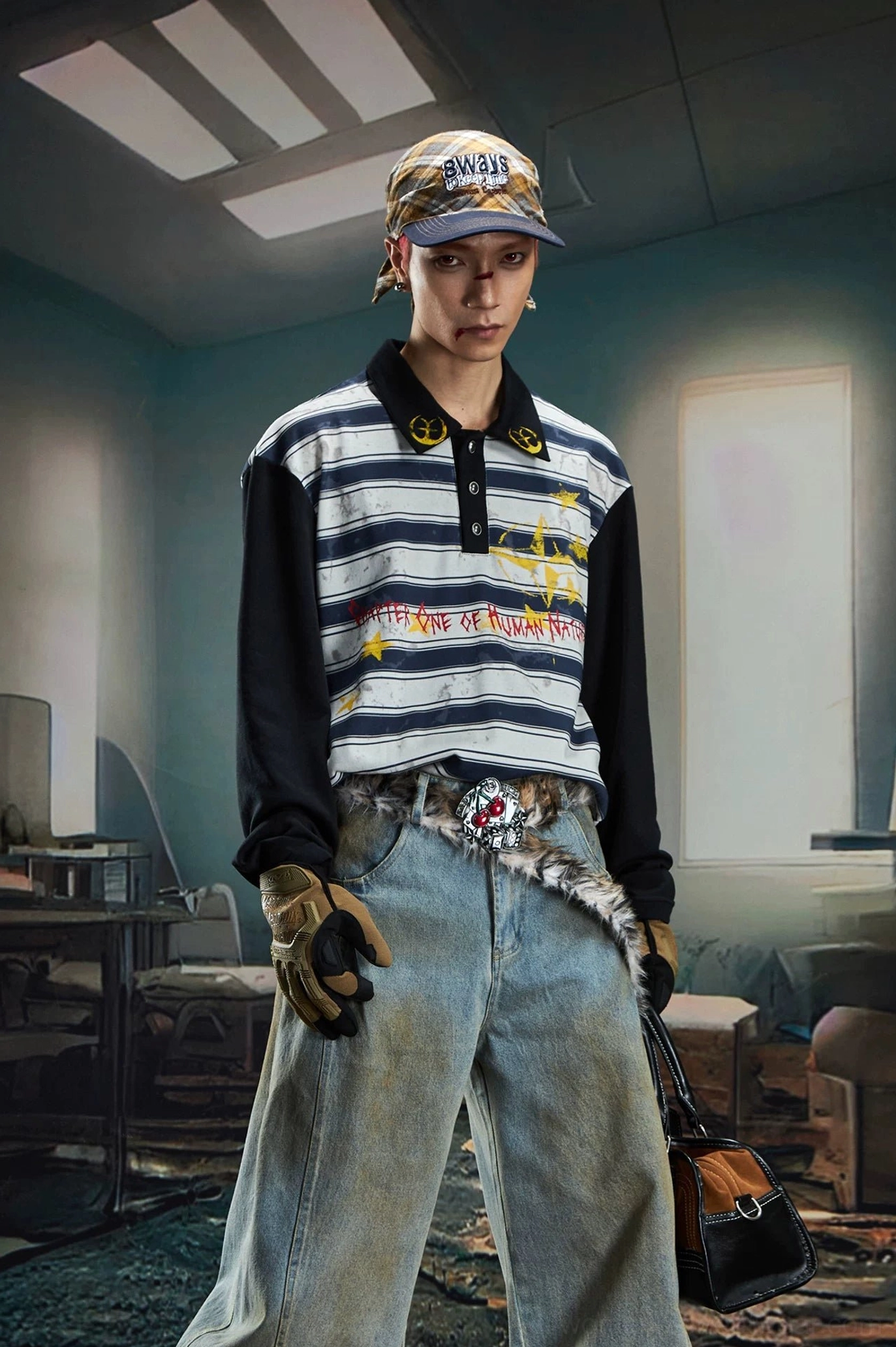 Close front view of a male model wearing a striped rugby polo shirt with graffiti graphic, work gloves, metal waist chain, and baggy jeans