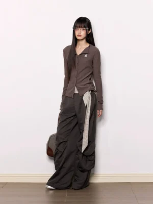 Dark gray wide-leg cargo pants with oversized side pockets and striped wrap sash belt shown from a side-front view