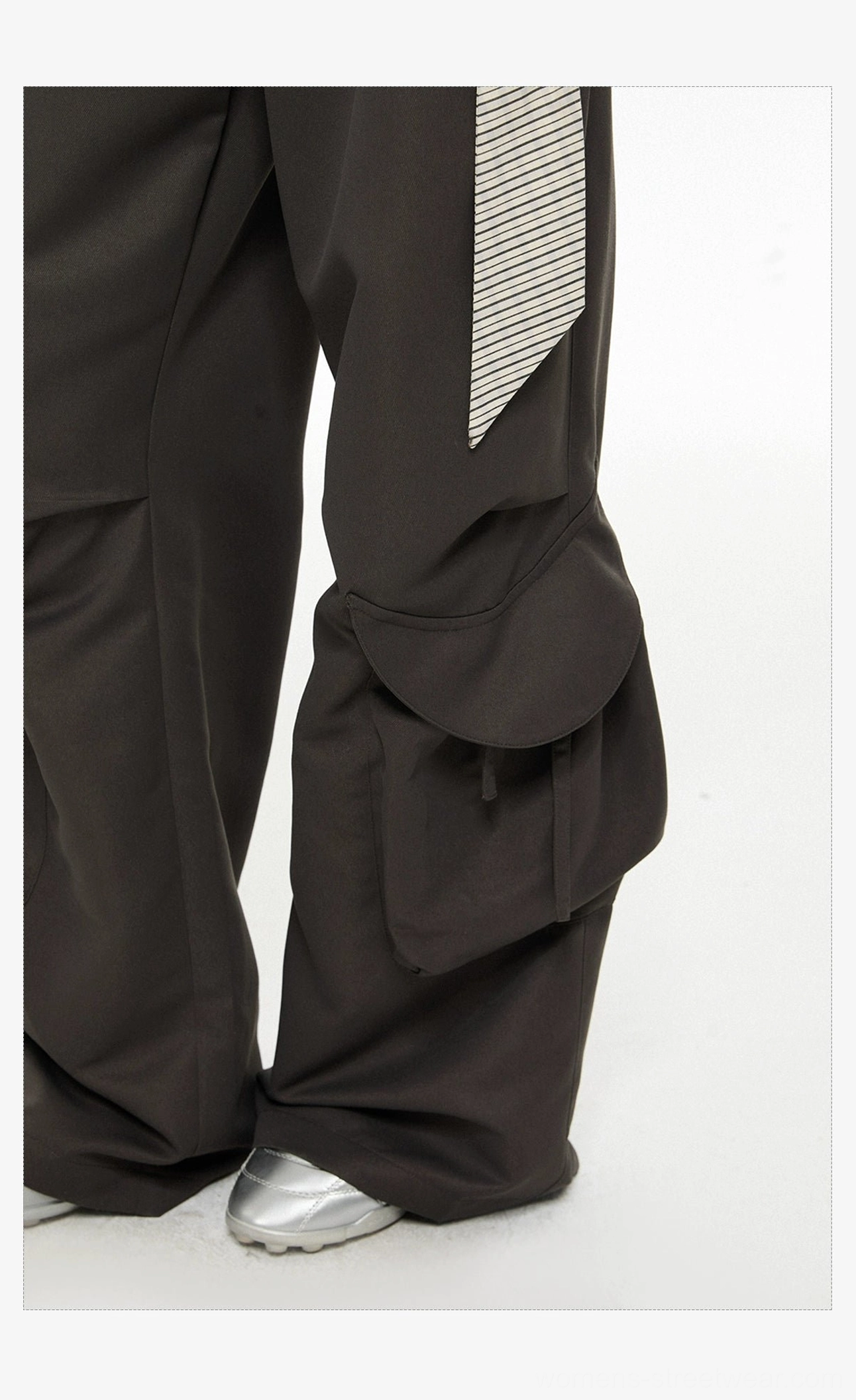 Close-up of oversized flap cargo pocket, hanging striped sash belt, and wide-leg dark gray pant construction