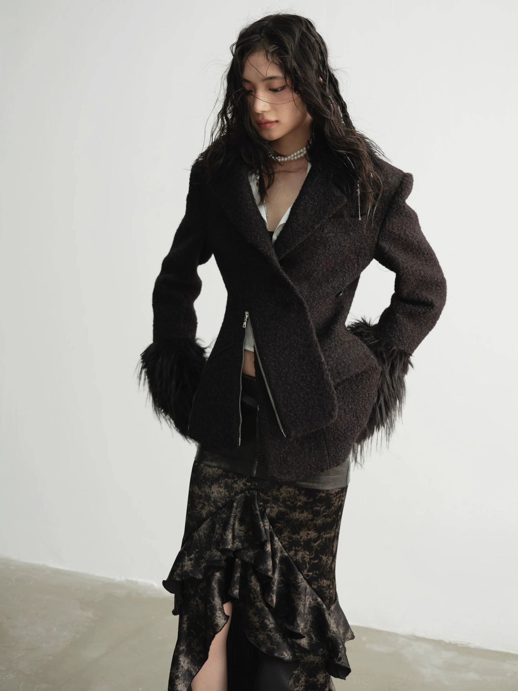 Side three quarter view of a structured faux fur trim coat with asymmetrical wrap front zipper shoulder pads and oversized cuffs