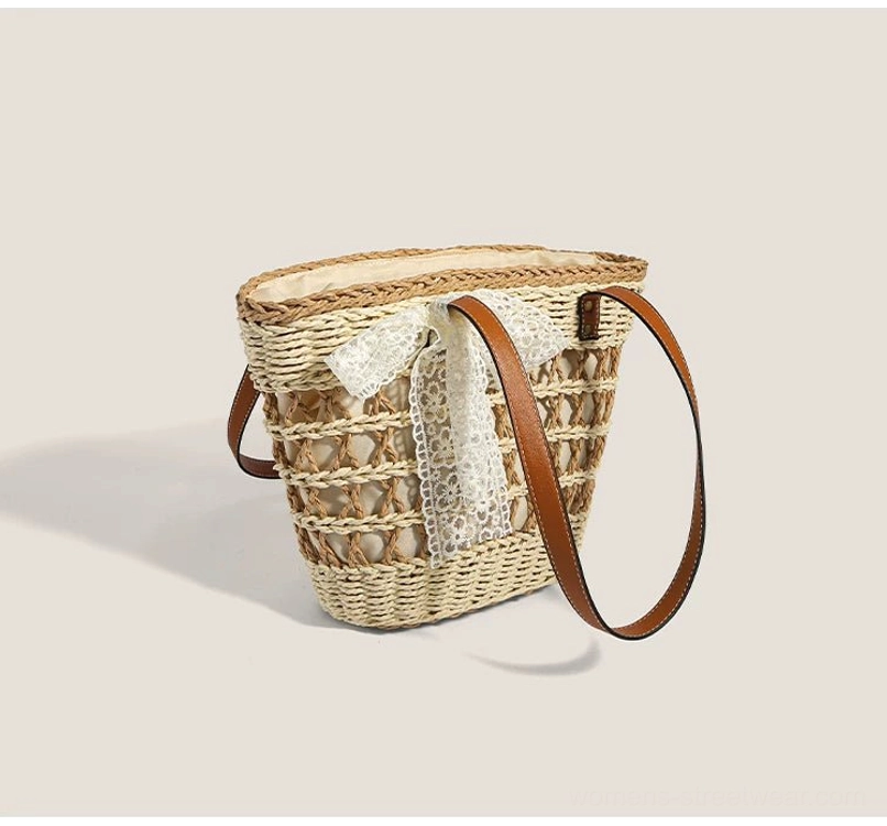 Front three-quarter view of structured hollow grid woven basket tote with brown straps and romantic white lace bow decoration