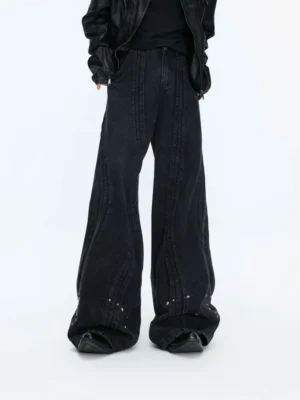Front full-body view of faded black studded wide-leg jeans with curved vertical seamwork, metallic hem rivets, and a black leather jacket streetwear outfit