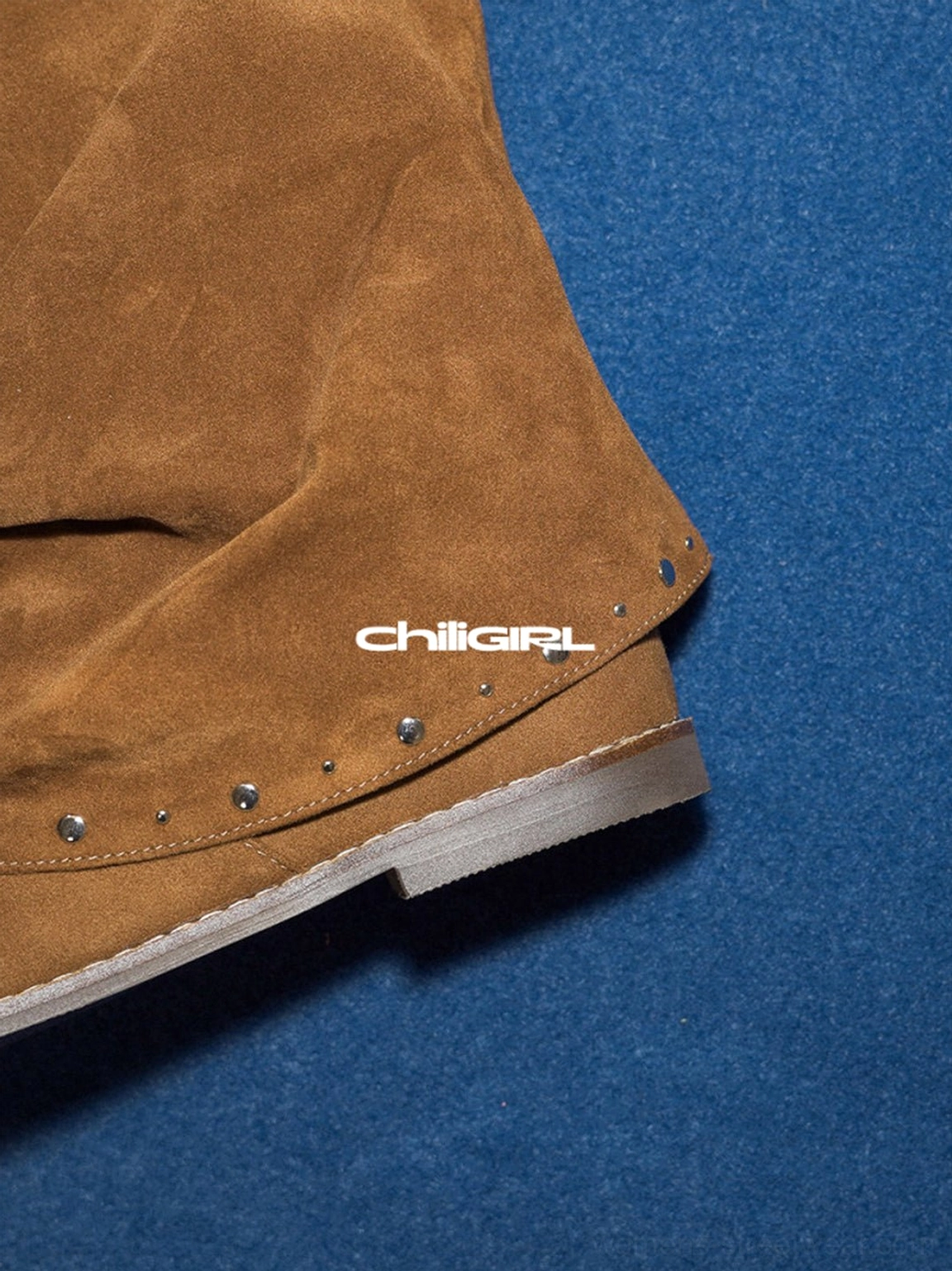 Close-up of brown suede tall sandal boots with silver stud trim, soft suede texture, ruched shaft and flat sole edge