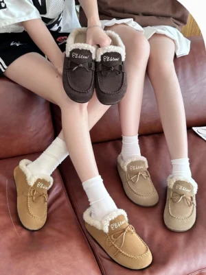 Two people wearing Coffee and Apricot suede-look shearling moccasin slippers with white socks on a leather sofa