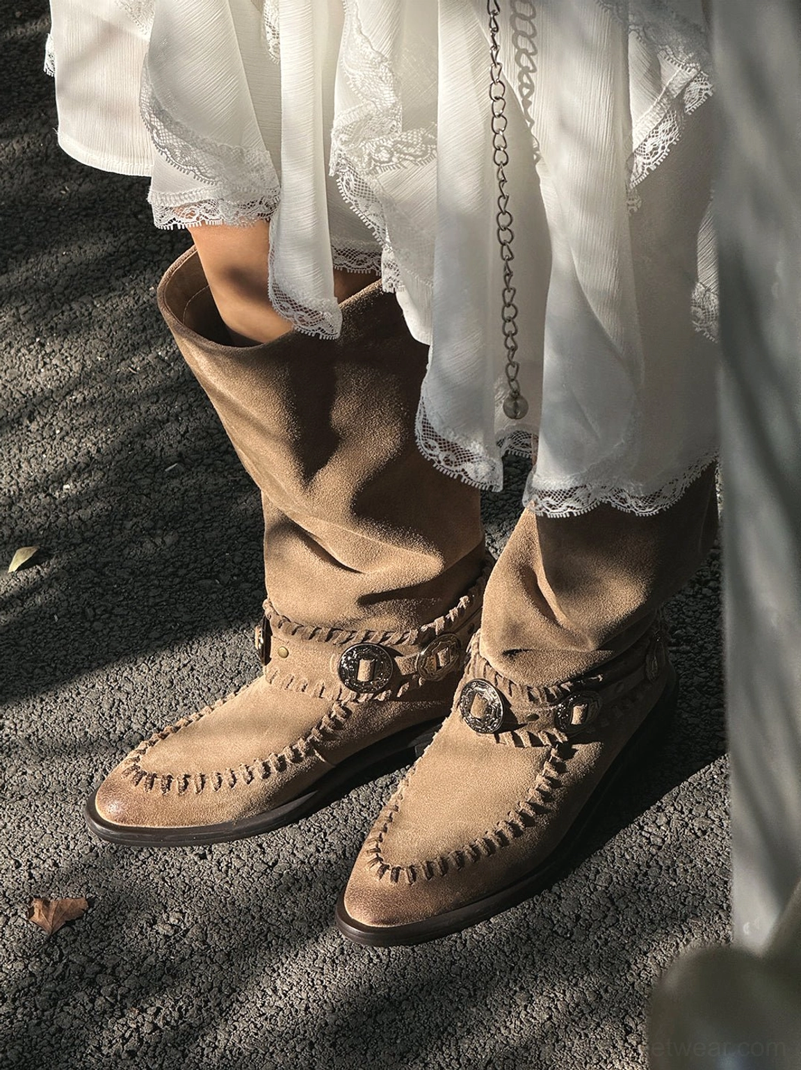 Suede-textured women's western boots with knee-high shafts, concho-inspired metal details, moc-toe stitching, and low heels