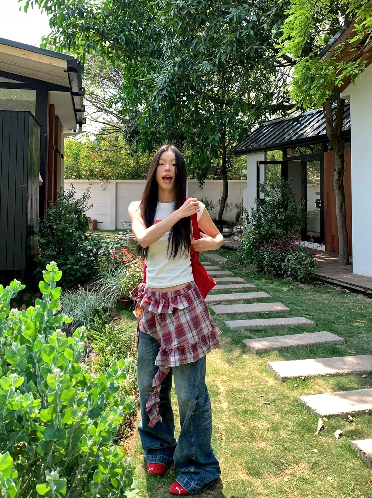 Sun-faded blue low-rise jeans styled with a plaid shirt tied around the waist and small red tote bag