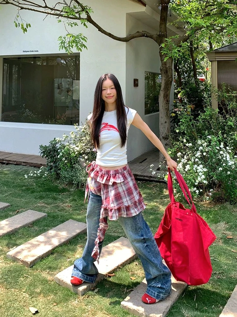Relaxed sun-faded wide-leg jeans with a plaid shirt tied at the waist and large red tote bag