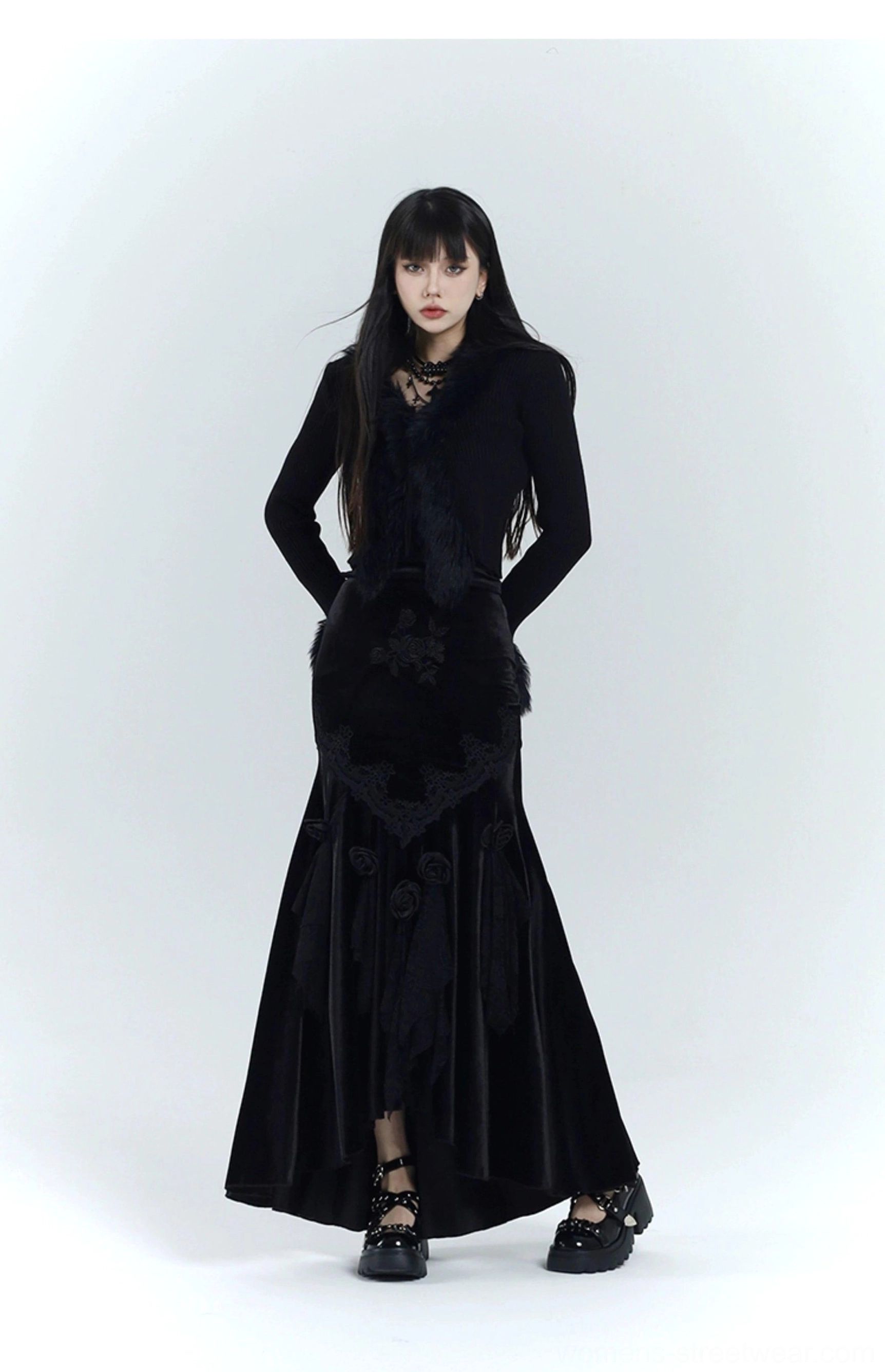 Full front view of a tailored black gothic velvet dress with slim fit, lace and rose skirt details, and soft faux fur trim