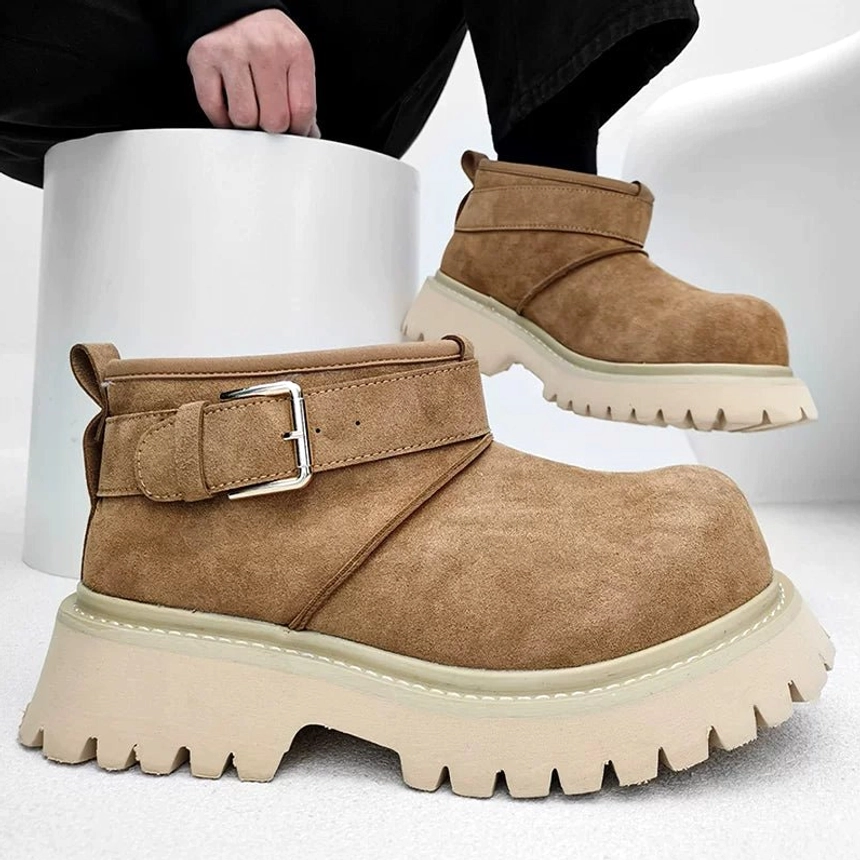Close-up front view of tan suede-finish buckle boots showing fleece lining, silver buckle, and off-white chunky sole