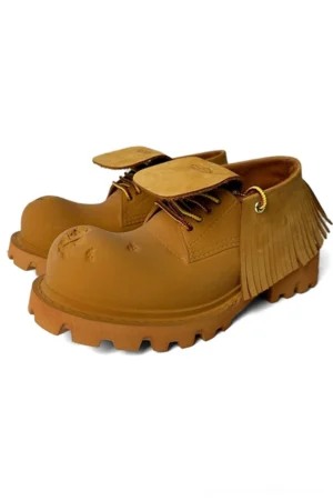 Tan platform derby shoes with removable fringe panels, contrast wax laces, and chunky lug sole shown in a three-quarter front view
