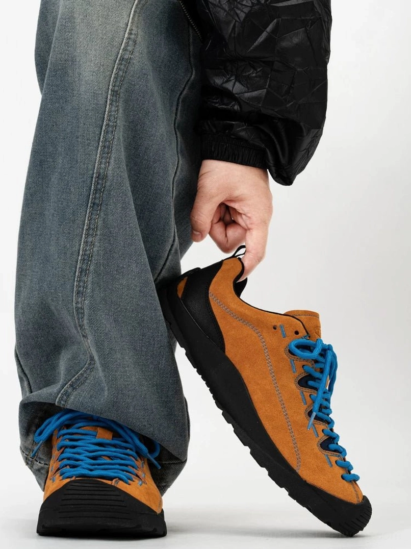 Tan low-top suede hiking sneakers with contrast blue laces, protective black toe cap and trail traction sole shown from side and front