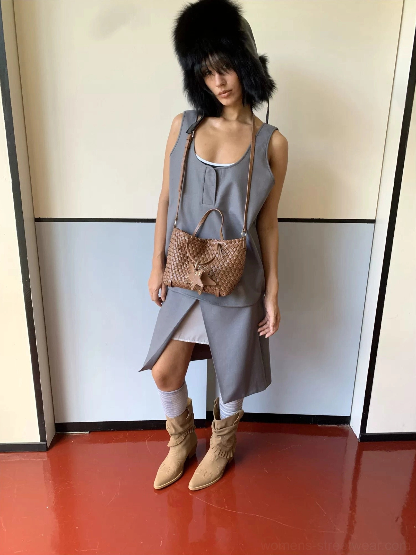 Tan mini woven star charm tote bag carried under the arm with dress and cowboy boots