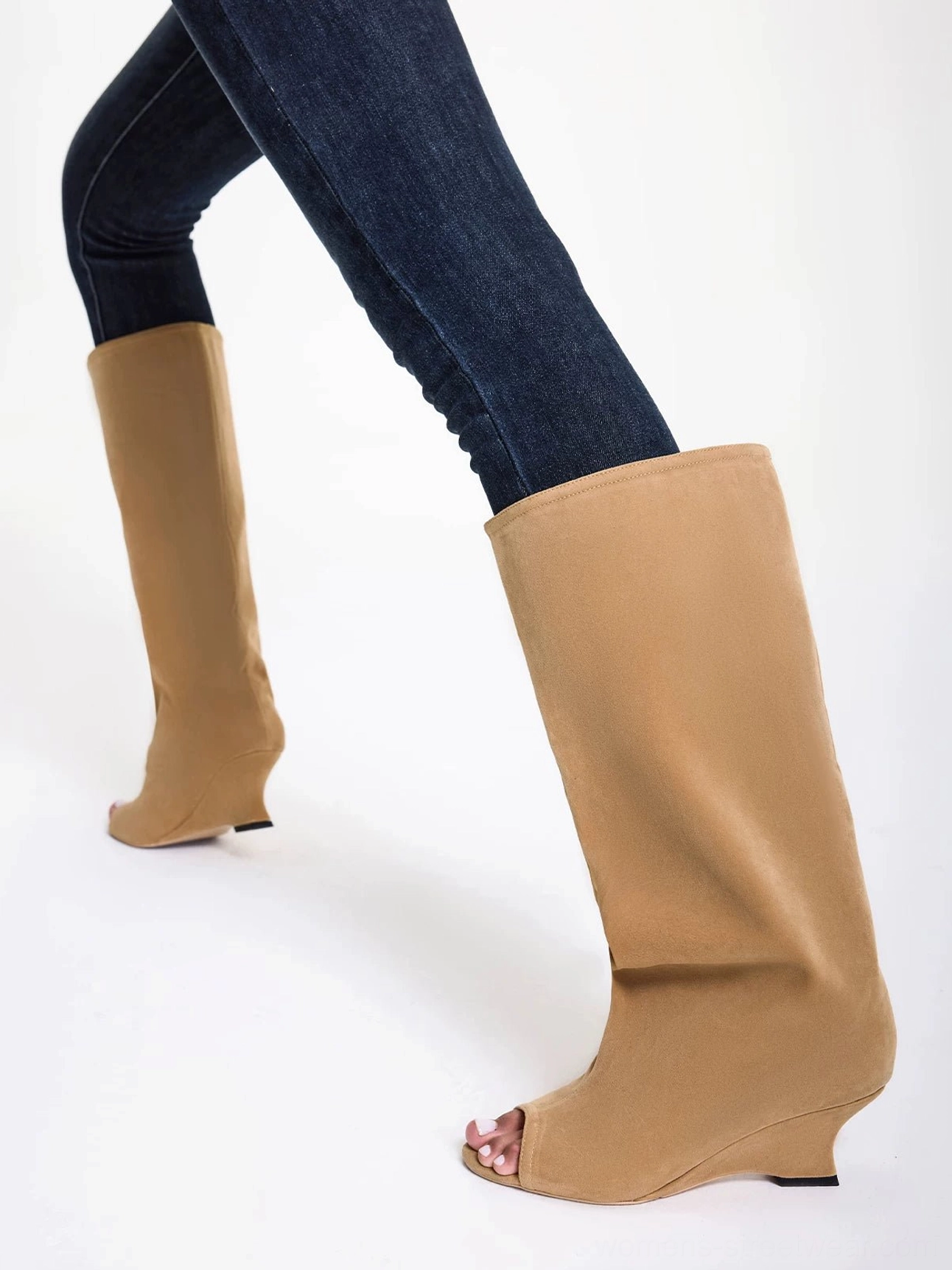 Tan peep toe wide shaft wedge boots styled with dark skinny jeans in a side view