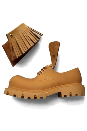 Side profile of a tan leather-look platform derby shoe with detachable western fringe detail and rugged EVA lug sole
