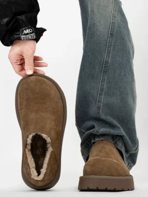 Overhead rear view of tan shearling-lined platform clogs worn with denim, highlighting the exposed faux fur collar, slip-on opening, and textured outsole