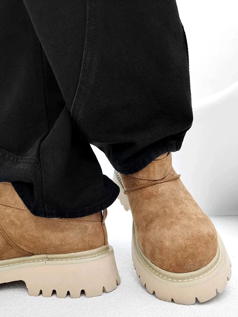 Side view of tan suede-finish platform ankle boots styled with straight-leg trousers