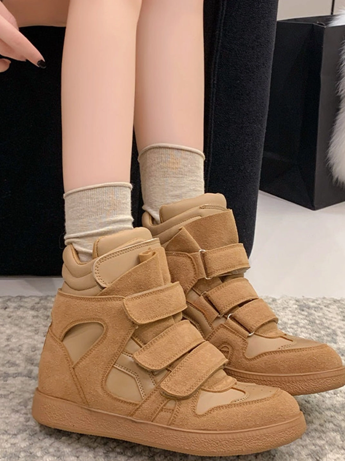 Tan suede Velcro hidden-wedge high-top sneakers worn from a rear overhead angle with layered straps, padded collar, and gum rubber outsole