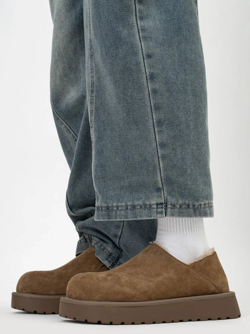Tan suede winter platform clogs worn with cropped blue jeans and white socks, showing the rounded toe, visible shearling trim, and chunky sole