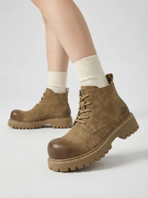 On-model wear shot of tan work boots with cream crew socks showing distressed leather finish and thick lug rubber sole tread
