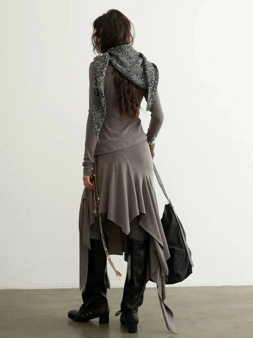 Back view of taupe asymmetric two piece fashion set showing irregular draped skirt hem, flowing waterfall panels, and heathered neutral color