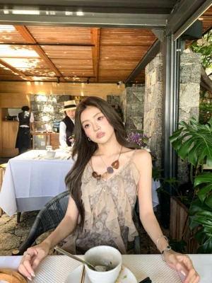 Taupe floral printed ruffle slip mini dress with V neckline and slim spaghetti straps worn at an outdoor restaurant table