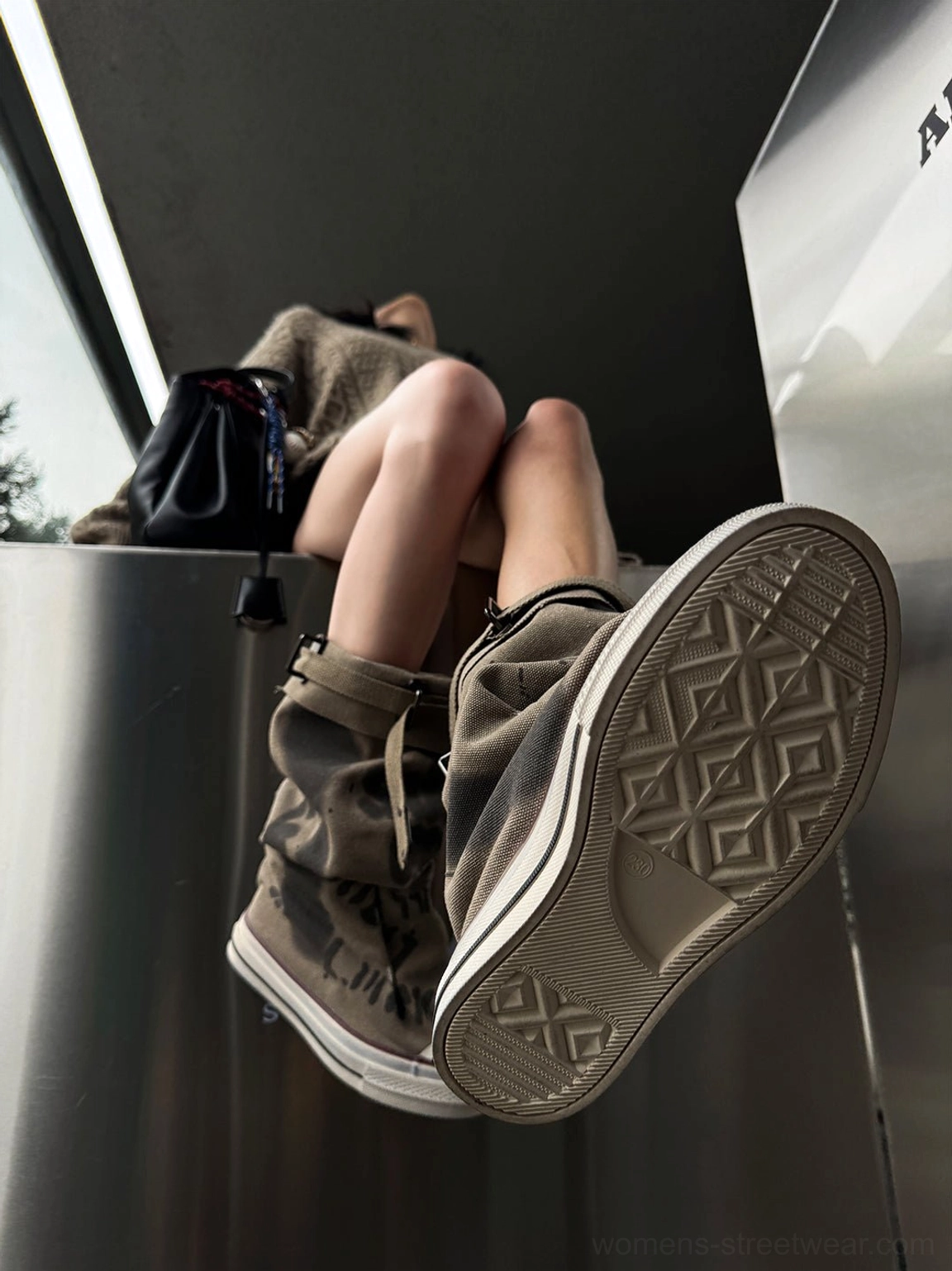Low angle view of taupe graffiti canvas slouchy tall boots showing chunky rubber platform outsoles and geometric tread pattern