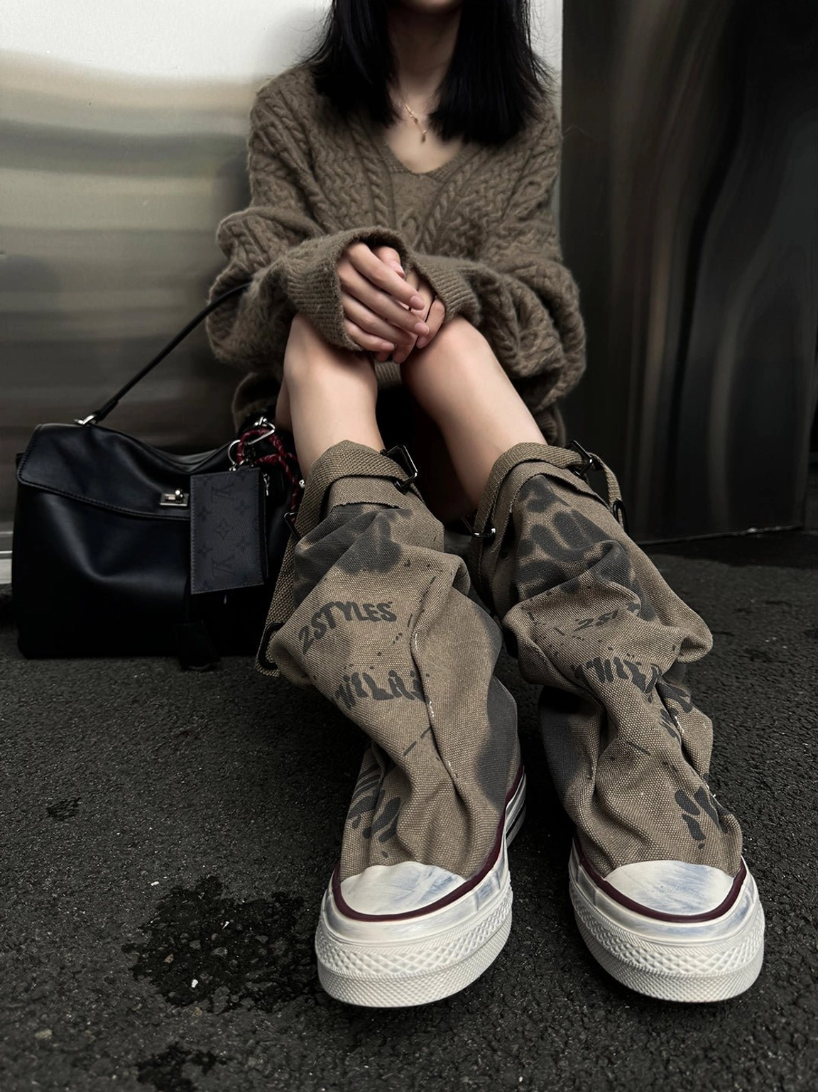 Top view of taupe graffiti canvas slouchy platform tall boots highlighting distressed rubber toe caps, laces, and faded graphic print