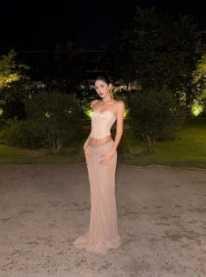 Taupe ruched V-waist maxi skirt styled with a strapless corset top in an elegant outdoor night garden setting